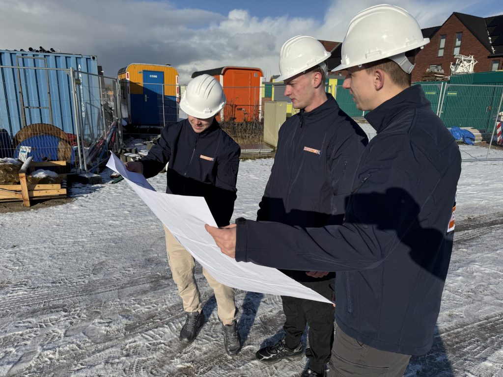 Vakmensen van Bouwsector Nederland met witte helm bespreken een bouwtekening bij woningen in aanbouw